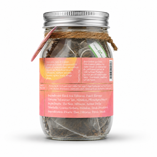 A glass mason jar filled with peach cold brew teabags, featuring a pink label with gold lettering, a silver metal lid, and a pink circular tag on the side. perfect for picnics, alfresco dining, dinner and garden parties, gifts , non alcoholic summer alternative.